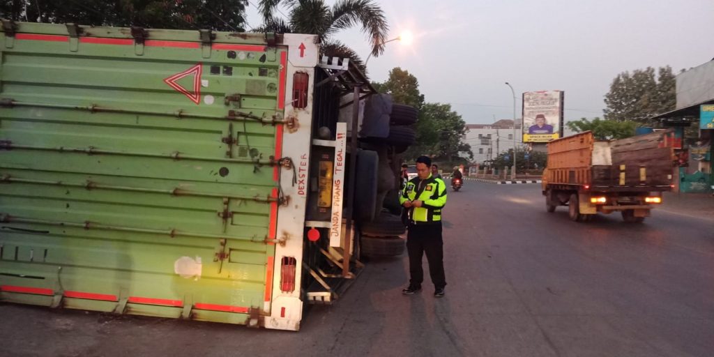 Caption : Petugas Satlantas Polres Cirebon Kota saat akan mengevakuasi Truk Tronton terguling dan tabrak warung. Foto : Ist